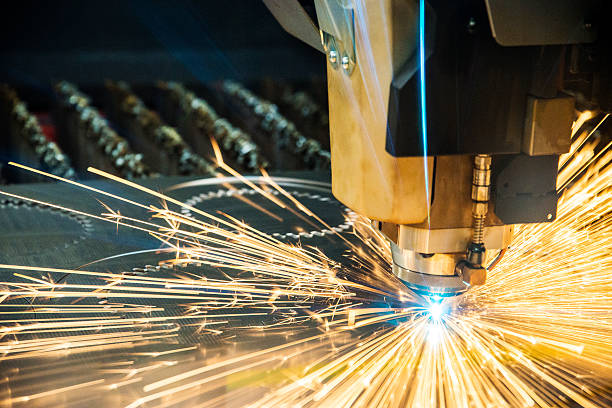 Metal fabrication. Laser cutter, cutting heavy-gauge sheet metal.  Sparks are flying off the tip.